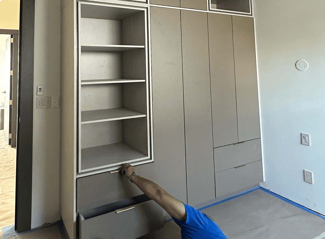Person assembling a gray wardrobe unit.